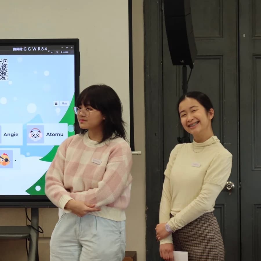 Two volunteers standing in front of a screen at the front of the room, at the start of the talk.
